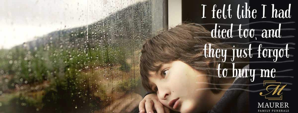 Young man resting his head against a rainy window